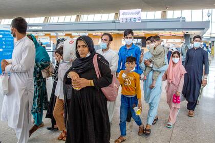 Familias evacuadas de Kabul, Afganistán, caminan por la terminal para abordar un autobús tras llegar al Aeropuerto Internacional de Dulles, en Virginia, el viernes 27 de agosto de 2021. (AP Foto/Gemunu Amarasinghe)