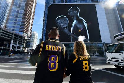 Fanáticos de Kobe Bryant con su camiseta, frente a una imagen que lo recuerda