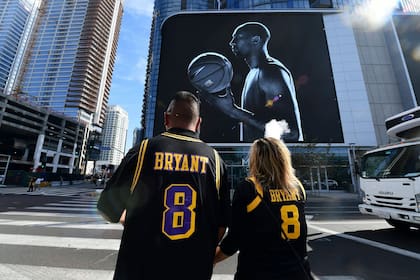 Fanáticos de Kobe Bryant con su camiseta, frente a una imagen que lo recuerda