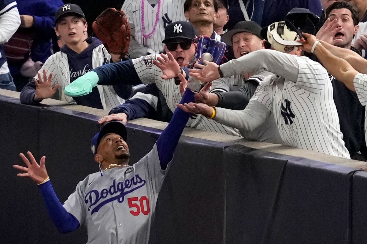 Fanáticos interfieren con la pelota de foul atrapada por el jardinero derecho de los Dodgers de Los Ángeles Mookie Betts en el cuarto juego de la Serie Mundial ante los Yankees de Nueva York, el 29 de octubre de 2024. (AP Foto/Ashley Landis)