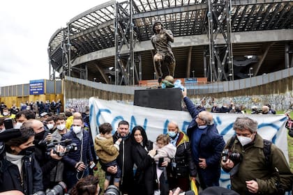 Fanáticos rodean la estatua de Maradona inaugurada en el primer aniversario de su muerte, frente al estadio que lleva su nombre, en Nápoles, Italia