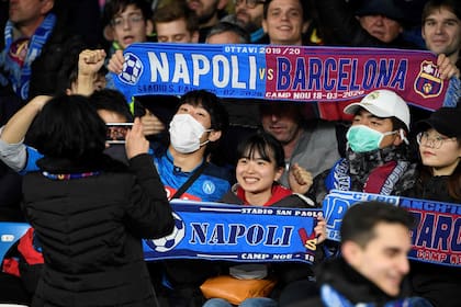Hinchas con bufandas conmemorativas del partido y con barbijos en prevención del coronavirus