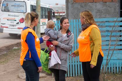 Fany, junto a otra de las voluntarias de El Arca, conversando con una vecina de la comunidad