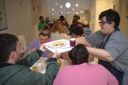 Fati, una de las socias e integrante de la unidad de cocina, le sirve el almuerzo a los socios. Ese día hay empanadas de pollo, que ellos mismos prepararon.