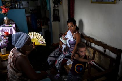 Fe María LLouvet abanica a su hija Disley Martínez mientras amamanta a su hijo recién nacido, durante un apagón matutino programado en Regla, Cuba, el lunes 1 de agosto de 2022. (Foto AP/Ramón Espinosa)
