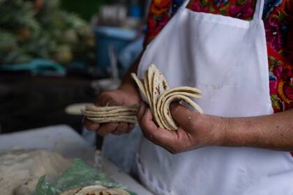 Felipa de Jesús Otzoy cuenta las tortillas que preparó en su puesto en un mecado de la Ciudad de Guatemala el 16 de octubre del 2021. (AP Photo/Moises Castillo)