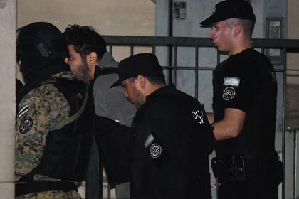 Fernando Sabag Montiel, en el centro a la izquierda, es conducido por la policía dentro del edificio de la Corte Federal en la avenida Comodoro Py, para testificar como principal sospechoso en el intento de asesinato contra la vicepresidenta de Argentina, Cristina Kirchner
