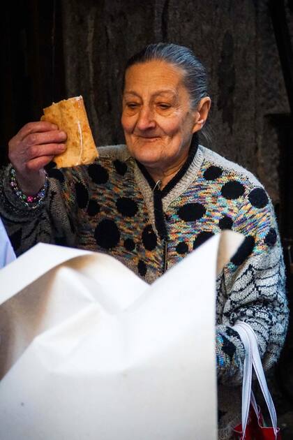 Una mujer toma una porción de pizza ofrecida por los "pizzaiuoli" napolitanos (fabricantes de pizzas) celebrando el reconocimiento de la UNESCO