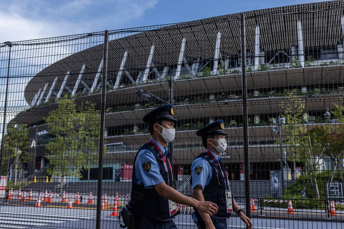 ficiales de policía con máscaras patrullan junto al Estadio Olímpico de Tokio el 21 de julio de 2021 en Tokio, Japón. A tan solo dos días de la ceremonia de apertura de los Juegos Olímpicos, Toshiro Muto, el jefe del comité organizador de Tokio 2020 ha declarado que no descartará la cancelación de los Juegos ya que más de setenta personas asociadas al evento ya han dado positivo por coronavirus.