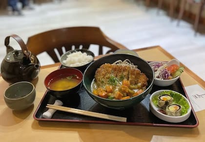 Fideos udon salteados con karē, panceta ahumada, langostinos y verduras de estación.