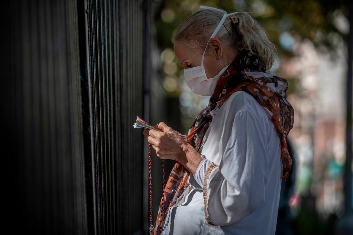 Fieles rezan en la reja perimetral de la Iglesia de Lourdes en Santos Lugares, Bs As