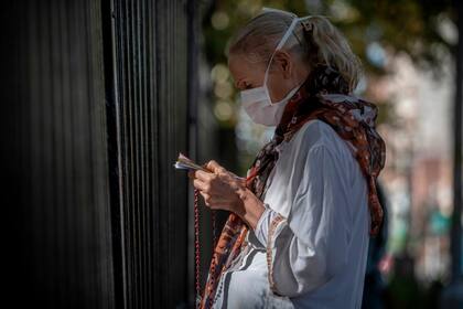 Fieles rezan en la reja perimetral de la Iglesia de Lourdes en Santos Lugares, Bs As