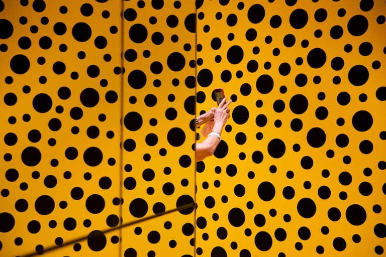 FILE -A woman takes a photo during her visit at the art work 'The Spirits of the Pumpkins Descended into the Heavens' by Yayoi Kusama, part of retrospective exhibition in the Tel Aviv Museum of Art, Israel, Monday, Nov. 15, 2021. (AP Photo/Oded Balilty, File)