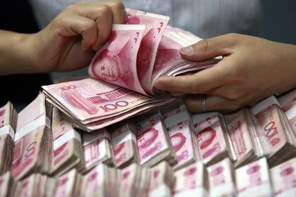 FILE - In this Friday, June 8, 2012 photo, a clerk counts Chinese banknotes at a bank in Huaibei in central China's Anhui province. Authorities in China have cracked the countryís biggest-ever underground banking network, which handled illegal foreign exchange transactions worth 410 billion yuan ($64 billion), state-run media reported Friday, Nov. 20, 2015. (Chinatopix via AP, File) CHINA OUT