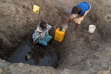 Mujeres recogen agua de un agujero en el lecho de un río, durante una sequía en Kenia