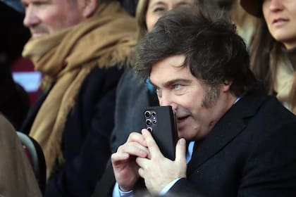 (FILES) Argentinian President Javier Milei talks on his mobile phone during the Argentine Rural Society's expo in Buenos Aires on July 28, 2024. Argentina's right-wing government stepped up its standoff with the media on February 6, 2026 by launching a social media account to "debunk" what it called media lies about libertarian President Javier Milei. (Photo by MARCOS BRINDICCI / AFP)