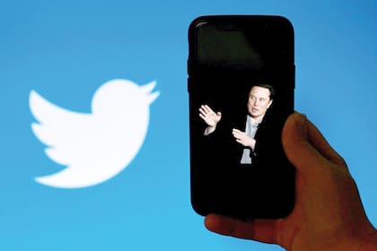 (FILES) In this file illustration photo taken on October 4, 2022, a phone screen displays a photo of Elon Musk with the Twitter logo shown in the background in Washington, DC. - The New York Stock Exchange did not permit trading on Twitter on October 28, 2022 after Elon Musk completed a $44 billion takeover of the social media platform. Twitter was listed among the companies experiencing a "trading halt," according to an NYSE notice that said the merger was "effective." (Photo by OLIVIER DOULIERY / AFP