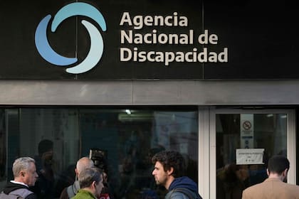 (FILES) The media wait outside the National Disability Agency (Andis) while it is being raided in Buenos Aires on August 29, 2025. The government of Argentina announced on December 30, 2025, the dissolution of the National Disability Agency (Andis), the subject of corruption allegations that implicated President Javier Milei’s sister, Karina. The agency's assistance functions, previously independent of the government, will be absorbed by the Ministry of Health without cutting the benefits it provides to more than 3 million users, Chief of the Cabinet of Ministers Manuel Adorni reported. (Photo by Juan MABROMATA / AFP)