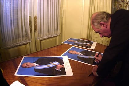 Firmando fotografías el 21 de diciembre de 2001, justo antes de abandonar en helicóptero la casa Rosada