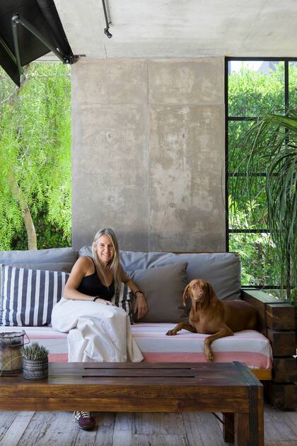 Florencia, dueña de casa, junto a Frida, una de sus perras de raza Vizsla. Allí, juego de sillón y mesa de lapacho (Hugo Tonti). Plantas (Viveros El Botánico).