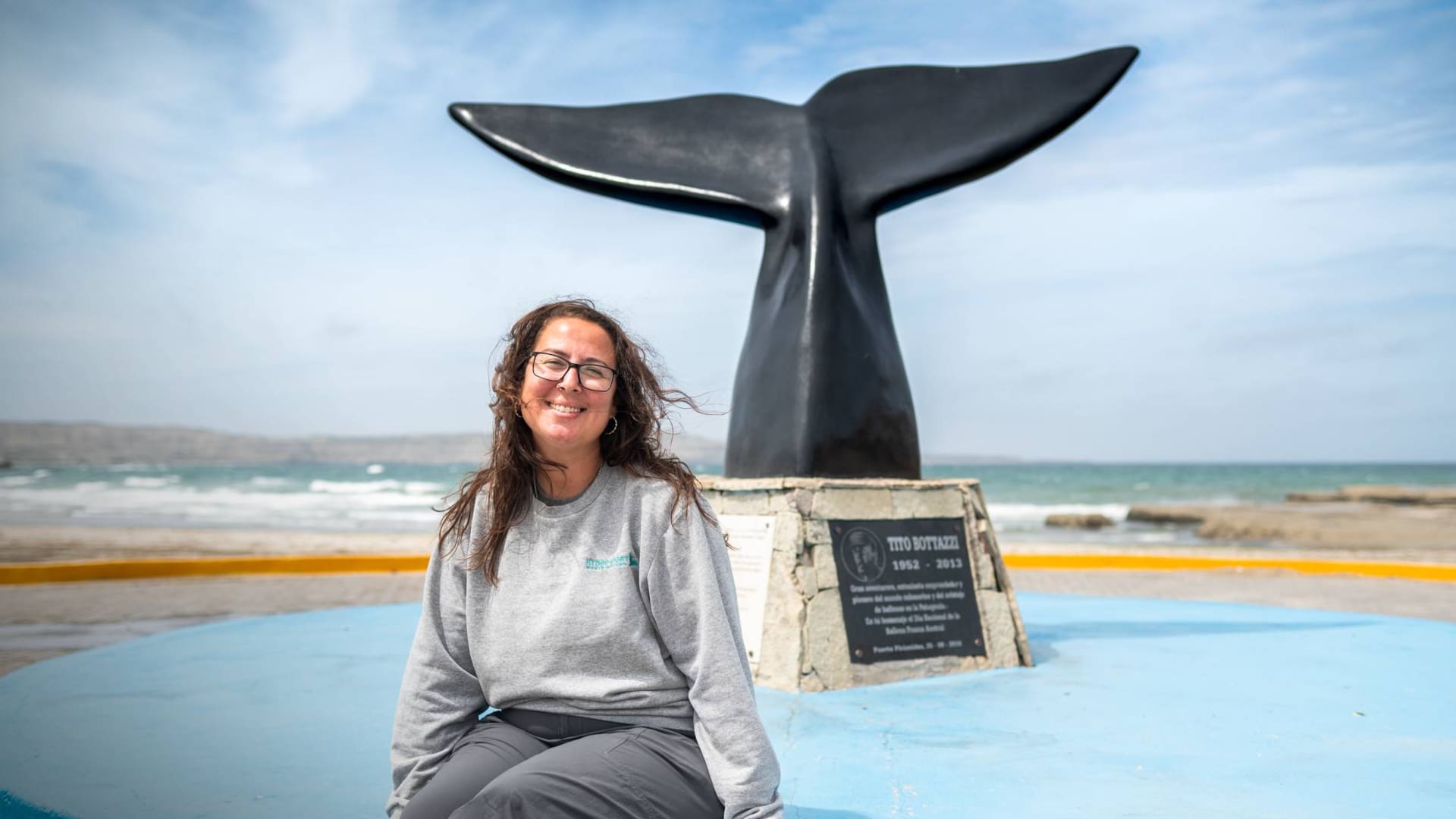 Florencia van Gelderen con el monumento que recuerda a su papá y a otros pioneros de la zona