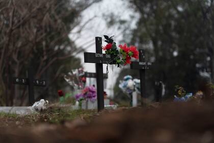 Flores artificiales adornan una cruz en una tumba en la sección COVID-19 del cementerio de la Chacarita en Buenos Aires, Argentina, martes 13 de julio de 2021. (AP Foto/Víctor R. Caivano)