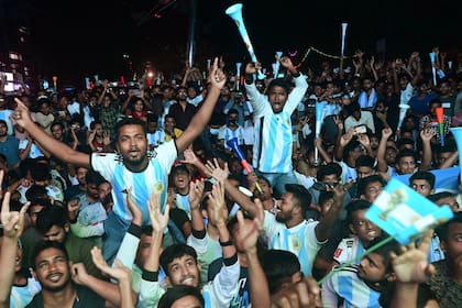 Football fans react as they watch the Qatar 2022 World Cup Group C football match between Poland and Argentina on a big screen, in Dhaka, on December 1, 2022. (Photo by Munir uz zaman / AFP)