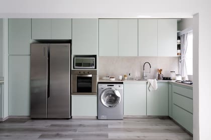 Foto de la cocina integrada d eun monoambiente con piso de vinílico. Heladera y muebles en verde.