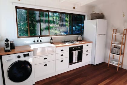 La cocina sigue la paleta de la casa: madera en la mesada y blanco y negro en el amoblamiento y los artefactos.