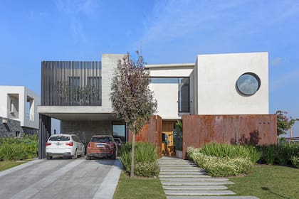 El acero Corten, el cerramiento vertical sobre el estacionamiento y la ventana circular definen áreas y le dan identidad a la casa desde la fachada. Trío de apliques ‘Adele’ (Idea).