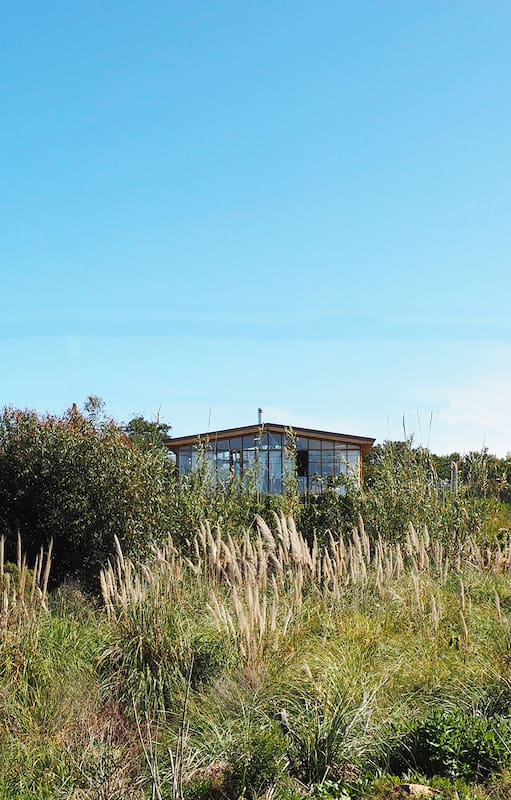 Foto de la fachada de una casa con deck de madera y jardín con pasto.