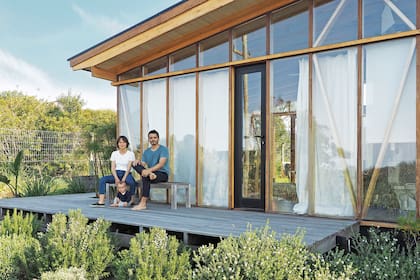 Delfina y Franco posan en su hogar hecho con estructura de multilaminado de eucalipto y vidrios dobles con cámara de aire.