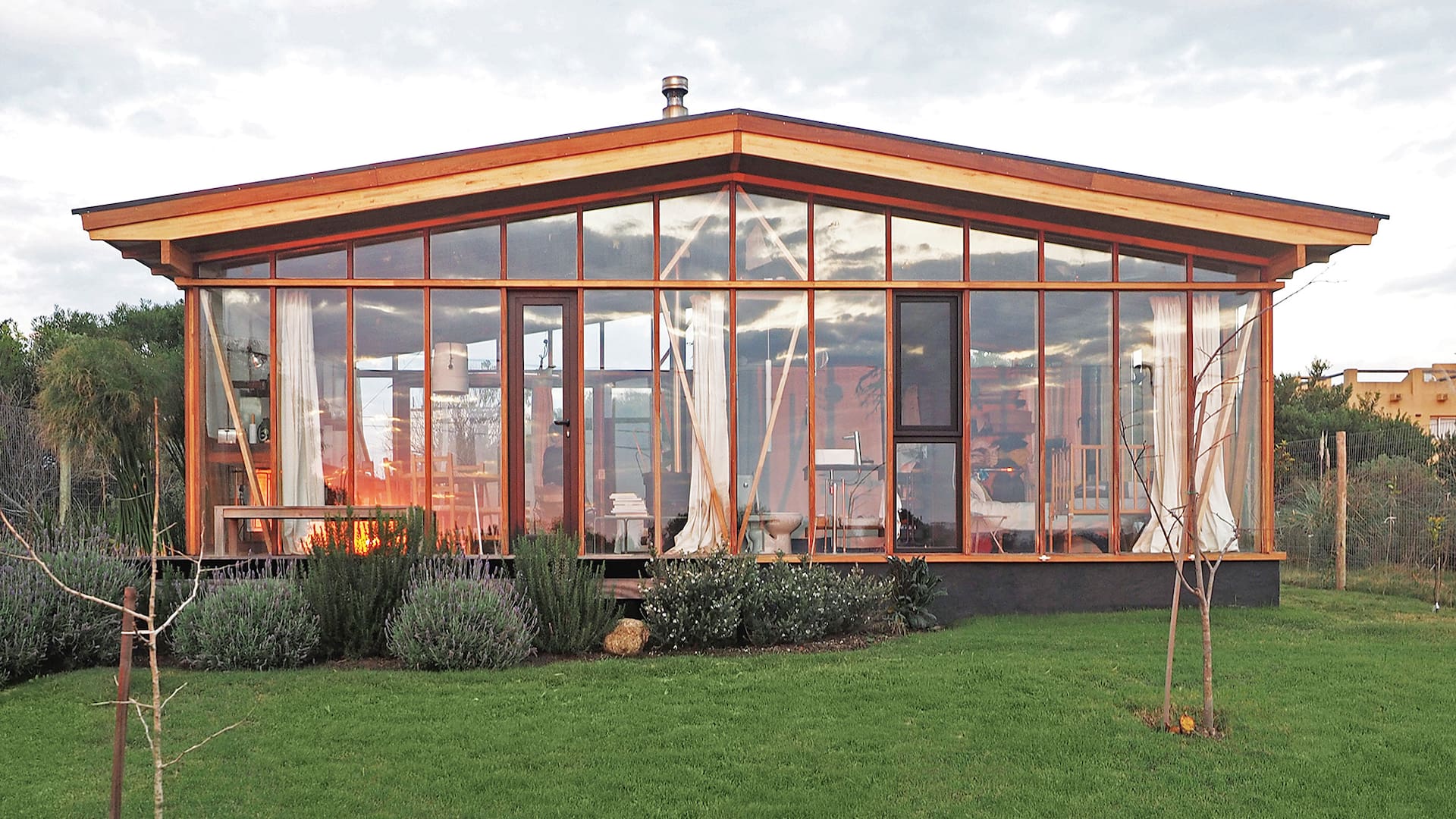 Foto de la fachada de una casa con deck de madera y jardín con pasto.
