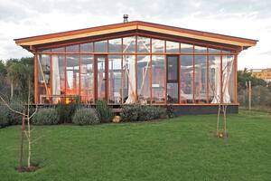 Foto de la fachada de una casa con deck de madera y jardín con pasto.