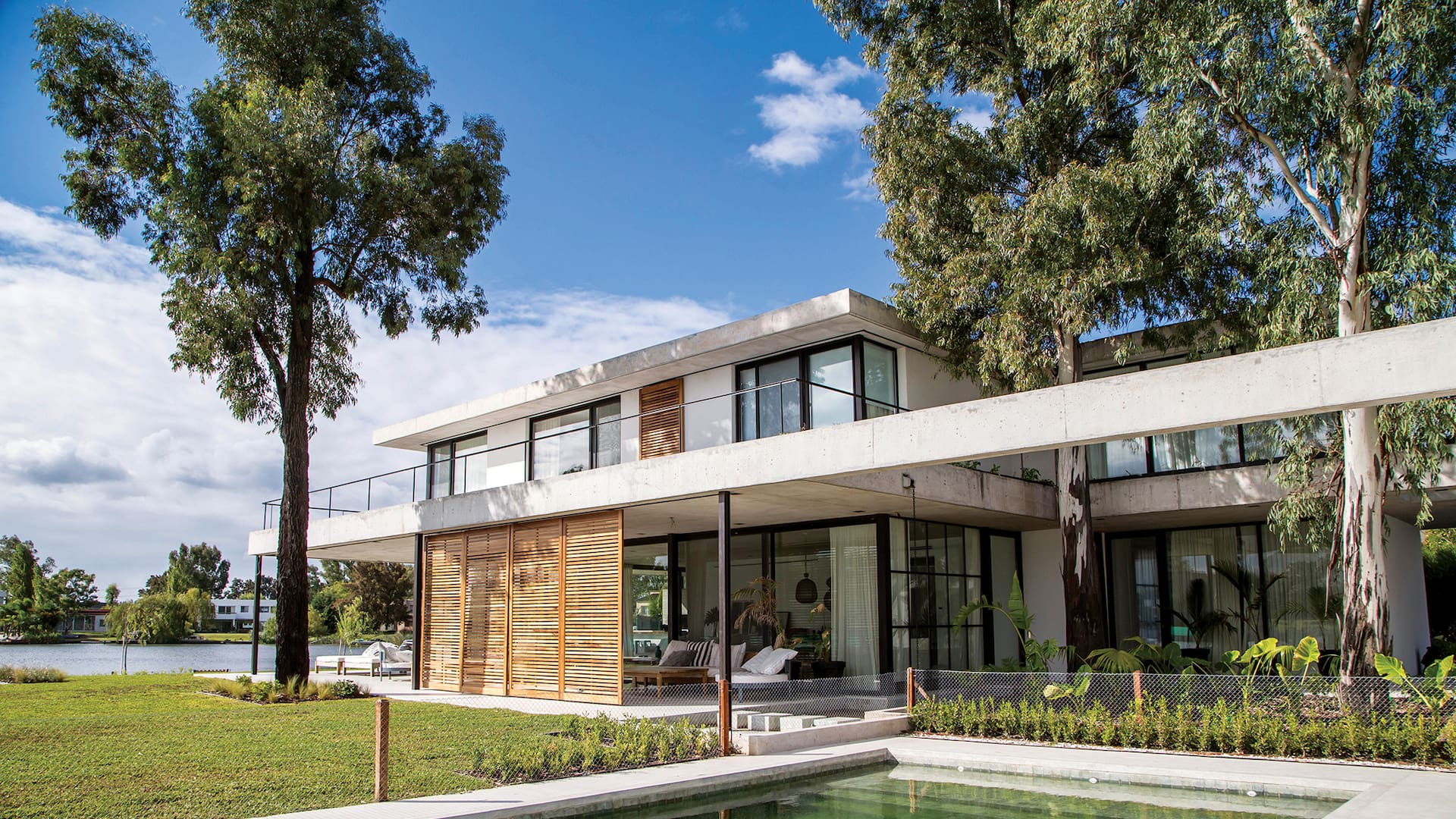 Foto de la fachada de una casa con jardín y pileta.