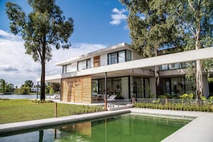 Foto de la fachada de una casa con jardín y pileta.
