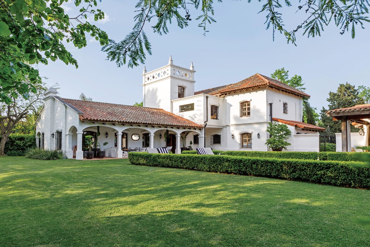 Foto de la fachada de una casa de estilo colonial con un gran parque verde.