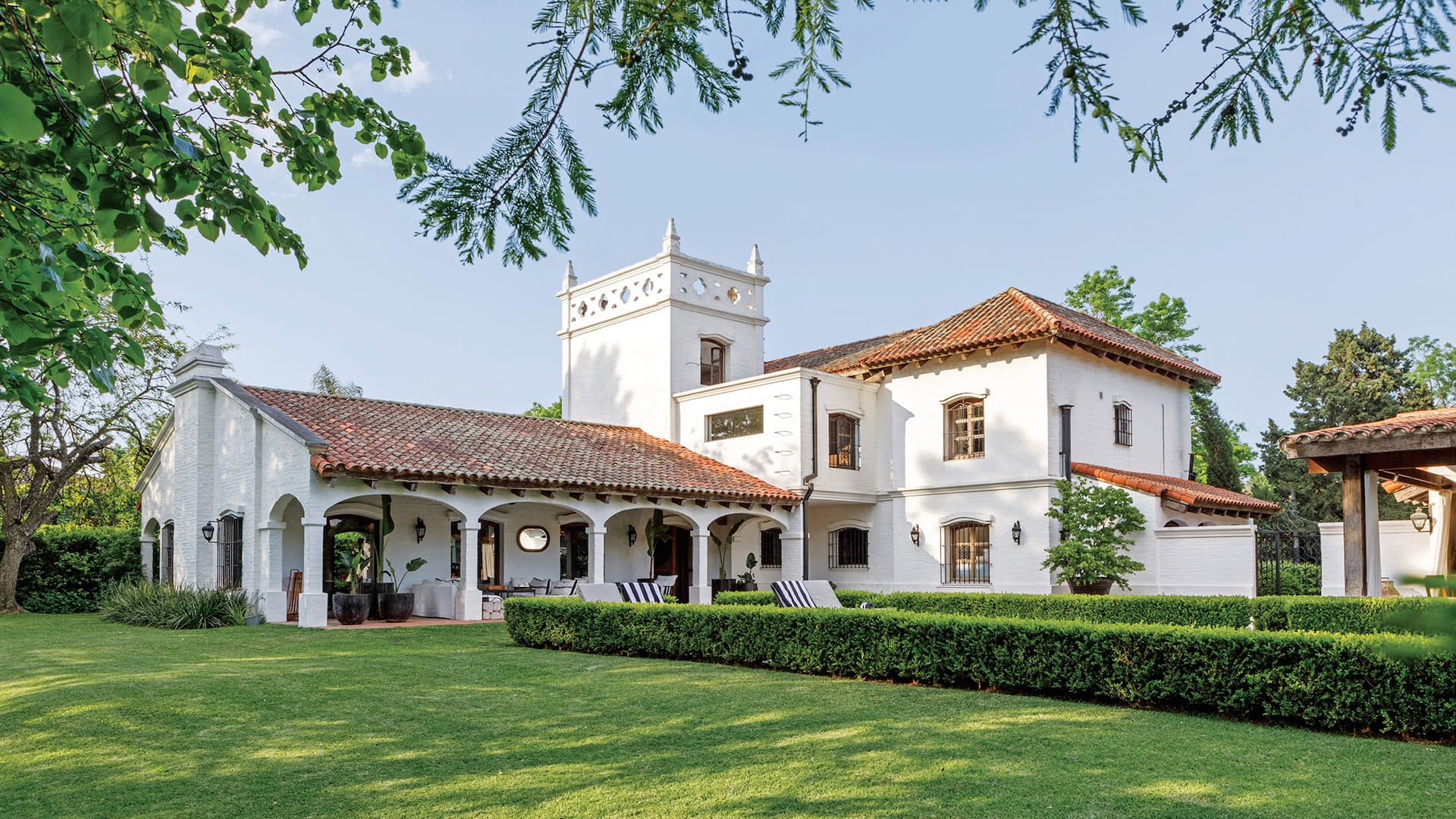 Foto de la fachada de una casa de estilo colonial con un gran parque verde.