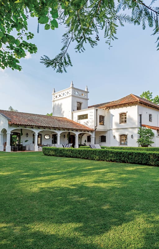 Foto de la fachada de una casa de estilo colonial con un gran parque verde.