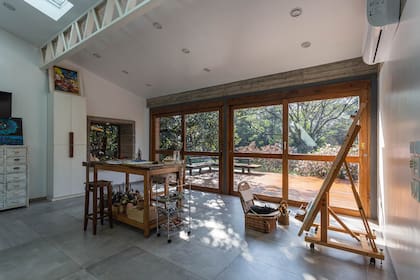 La banqueta de madera permite trabajar en altura y desplazarse por el espacio con facilidad. Además de los enormes ventanales, las ventanas en el techo suman luz natural la mayor parte del día. Así, Graciela puede moverse por el espacio, siempre bien iluminado.