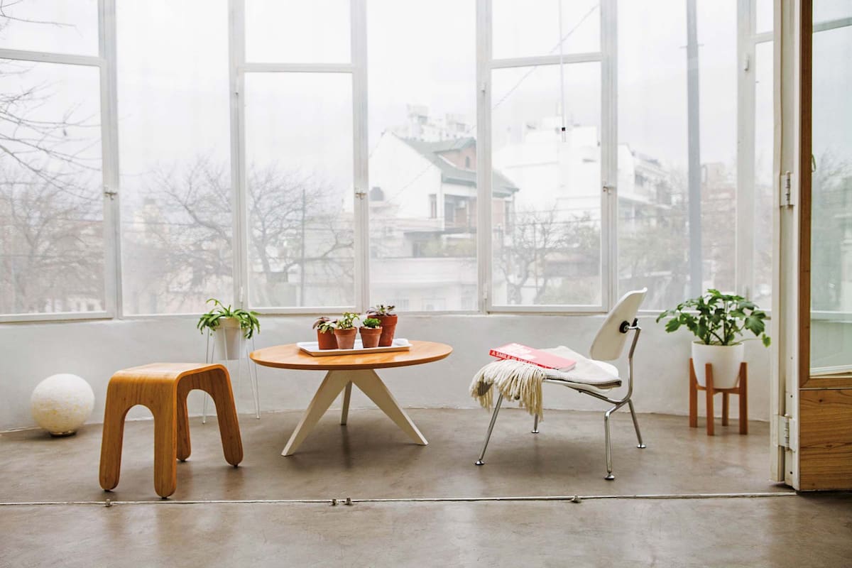 Foto de un balcón con mesa ‘Ostende’, silla blanca Eames, banco ‘Esteban’ y manta con flecos.