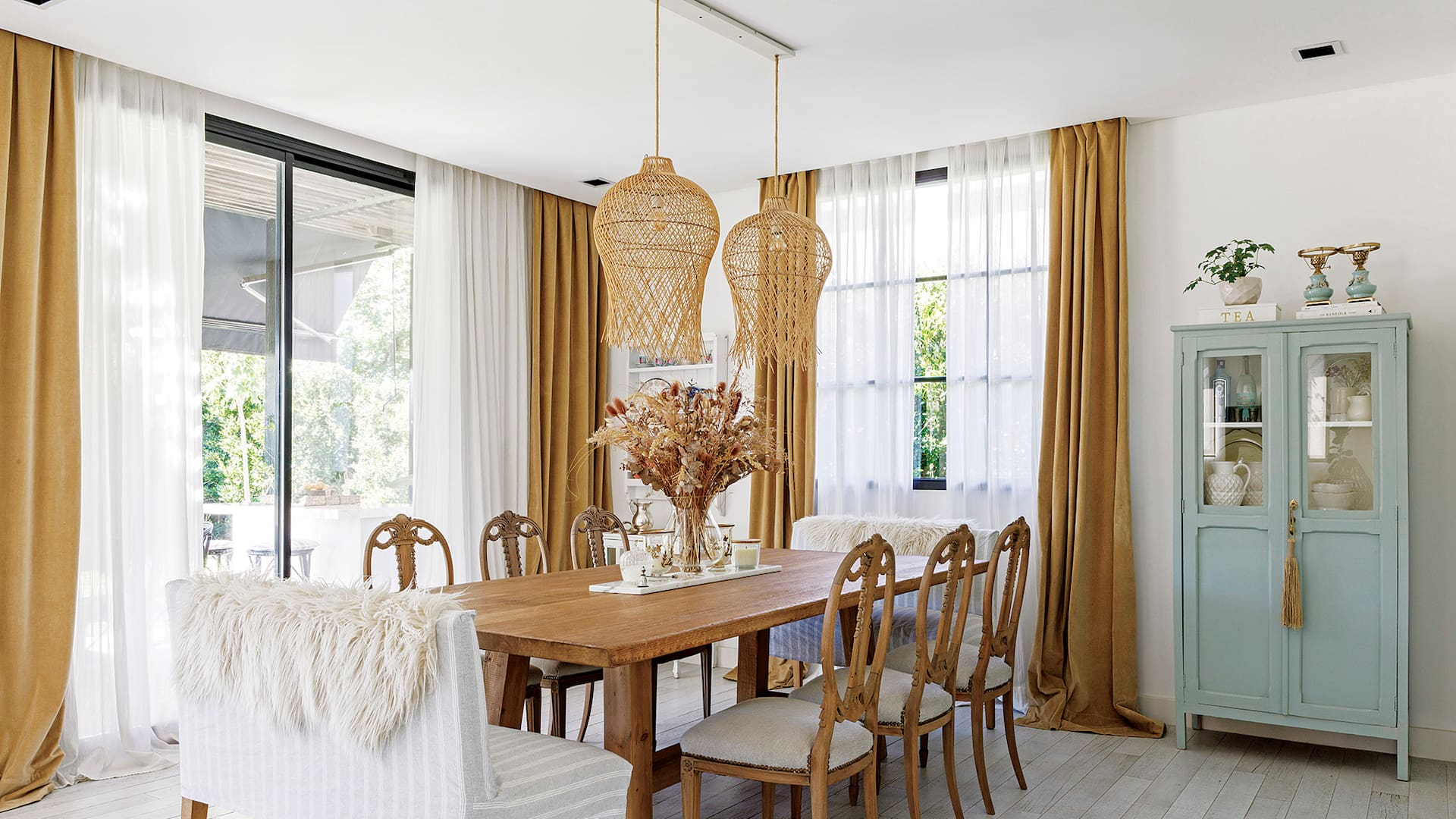 Foto de un comedor con cortinas traslúcidas enmarcadas por un cantonnier de terciopelo arena.