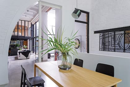 Sobre la mesa del comedor, florero de vidrio humo con arreglo verde (Casa María Paula).