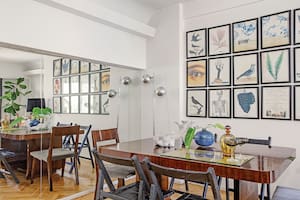 Foto de un comedor con mesa, mix de sillas, lámpara de pie. Licorera ámbar y copas vintage sobre una bandeja de vidrio.