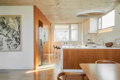 Foto de un comedor integrado a la cocina con muebles de madera y gran obra de arte.