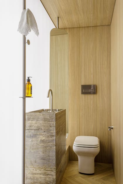 Perchero y soporte de espejo en acero inoxidable (Inox Atelier). Espejo (Aura Home). Inodoro corto 'Limay' (Ferrum). Grifería 'Slice' (Novum).