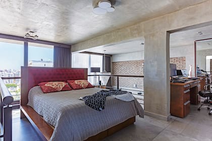 La cama tiene una estructura de madera y cabecera en rojo.