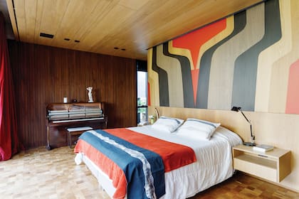 Paredes y cielo raso revestidos en goiabao. Pie de cama y almohadones ‘Akira’ (Pez Koi). Sobre la alfombra (Elementos Argentinos).