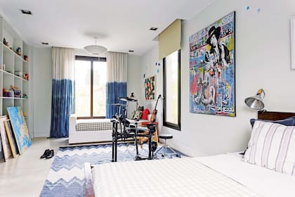 Junto a la ventana con cortinas teñidas (May Arizaga), cama blanca de una plaza, cuadro de banderas de Yaya Firpo (Diderot Art) y mesa circular ‘Quiti’ (Las Marinas).
