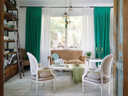 Biblioteca (Juanes Decoraciones). Sillas, mesa ratona y sillón (Arlequín Antigüedades). Lámparas de techo (María Pérez Deco). Cortinas en lino (De Levie).